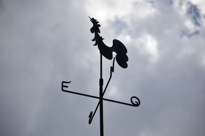 Low angle view of weather vane against sky