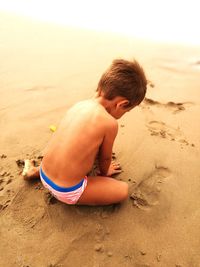 Full length of shirtless boy on sand at beach