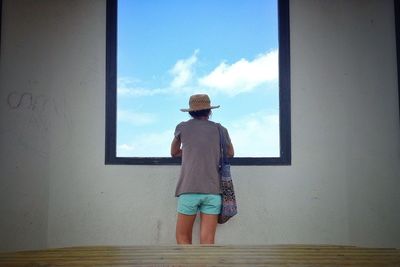 Rear view of a woman looking through window