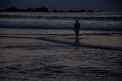 Silhouette man on beach against sky during sunset