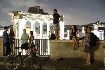 People on bicycle in city against sky