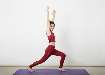 Full length of woman with arms raised against white background