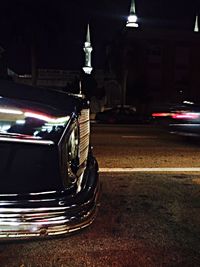 Cars on illuminated city against sky at night