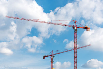 Low angle view of cranes against sky