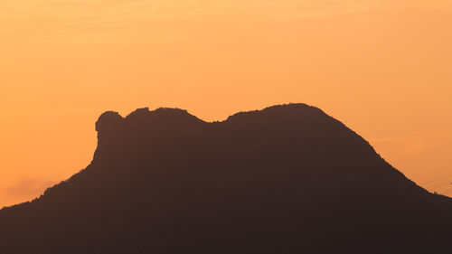 Scenic view of silhouette mountains against orange sky