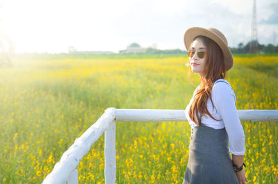 Young woman wearing sunglasses while standing on field