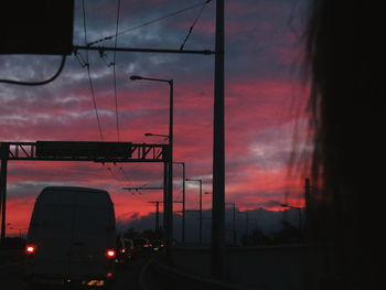 Cars on road against sky at sunset