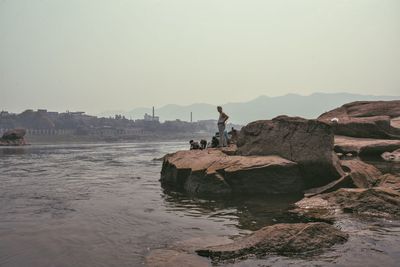 Woman standing on rocks by sea