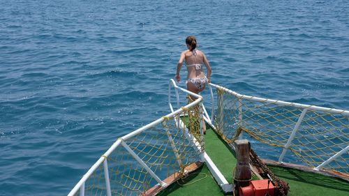 Rear view of woman standing on diving platform over sea