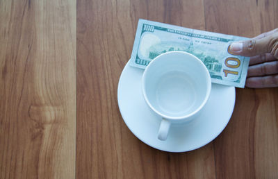 Close-up of hand holding coffee cup on table