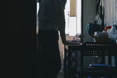 Low section of man leaning against table