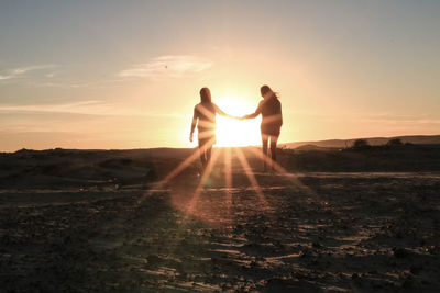 Silhouette couple standing against sky during sunset