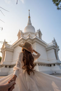 Low angle view of woman by building against sky