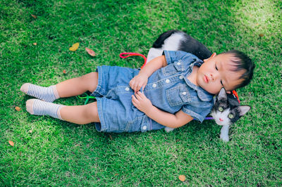 Full length of boy lying on cat outdoors