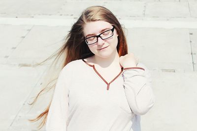 Portrait of smiling young woman standing against wall