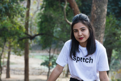 Young woman against trees