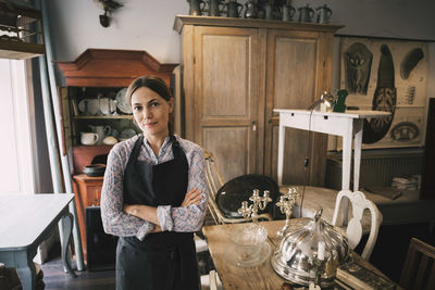 Portrait of confident female owner standing in antique shop