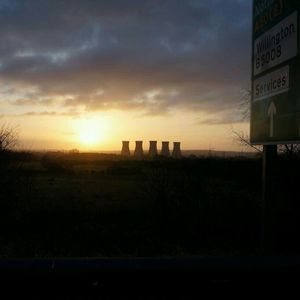 Scenic view of landscape against cloudy sky at sunset