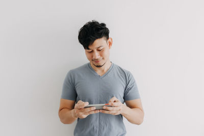 Young man using smart phone against white background