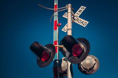 Low angle view of railway signal against clear blue sky