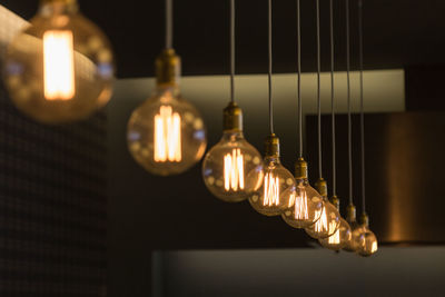 Low angle view of illuminated light bulbs hanging from ceiling