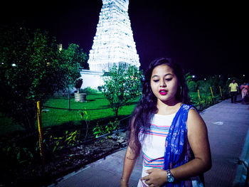 Portrait of beautiful woman standing in city at night