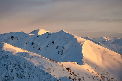 Scenic view of snowcapped mountains against sky during sunset