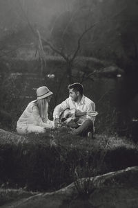 Couple sitting on grass in forest