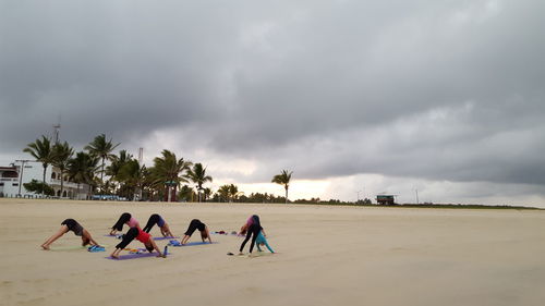 Side view of people exercising on beach
