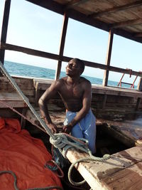 Full length of shirtless young man in sea against sky