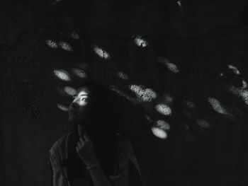 Portrait of young woman standing against wall