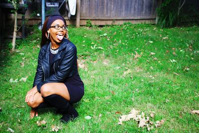 Woman crouching while sticking out tongue at back yard