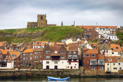 Buildings by river against sky