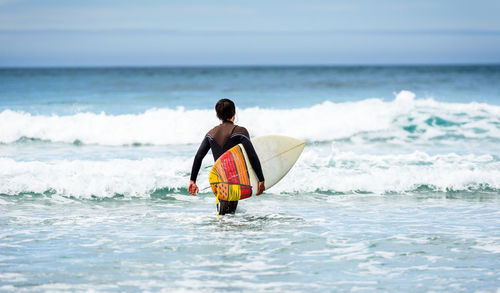 Full length of man surfing in sea against sky