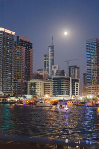 River and illuminated city buildings against clear sky