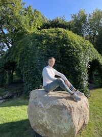 Man sitting on rock against trees