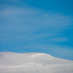 Scenic view of snow hill against blue sky