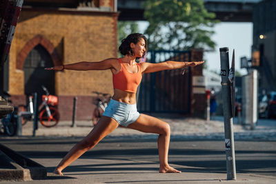 Full length of woman exercising on footpath against building