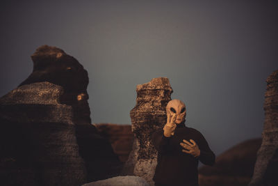 Portrait of alien gesturing against rock formation