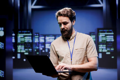 Young man using digital tablet while standing in office