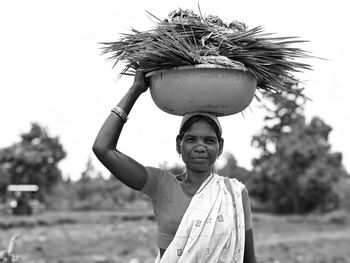 Portrait of smiling woman carrying basket on head