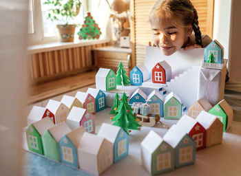 Origami advent calendar, paper craft. girl looking upon paper houses with number and paper tree