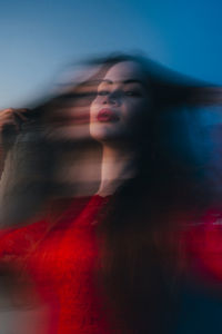 Portrait of young woman looking away against sky