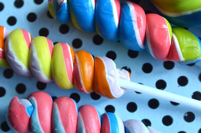 Multicolor hard candy lollipops on sticks on spotted paper closeup 