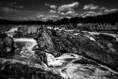 Water splashing on shore against sky