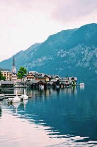 Houses by lake and mountains against sky