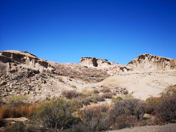 Scenic view of rocks against clear blue sky