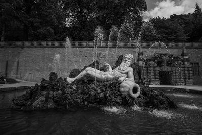 Statue by lake against trees