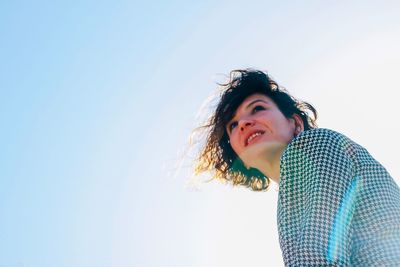 Portrait of smiling young woman against clear sky