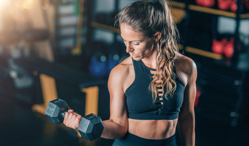 Female athlete doing biceps exercise with dumbbells. strength training.